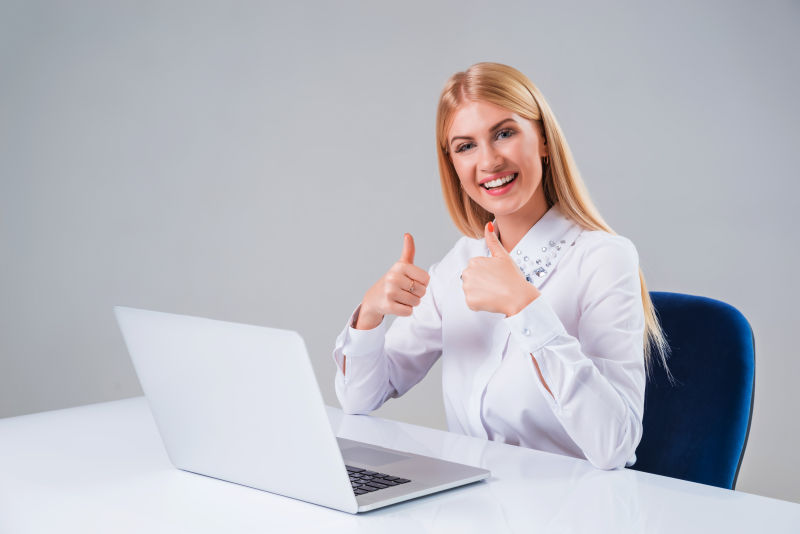 笔记本电脑前开心举着大拇指的女人