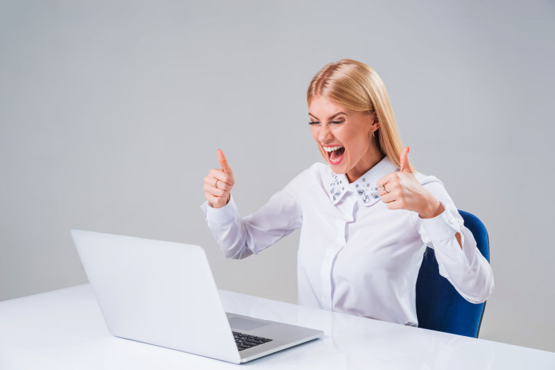 用笔记本电脑工作开心举着大拇指的女商人