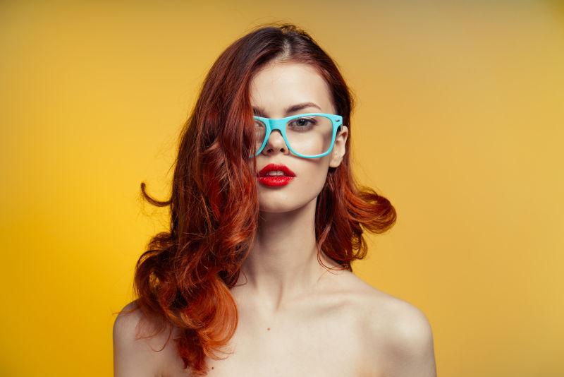 黄色背景前的棕色长卷发年轻美女