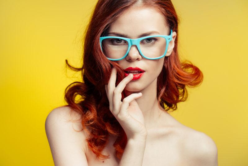 黄色背景前的棕色卷发年轻美女