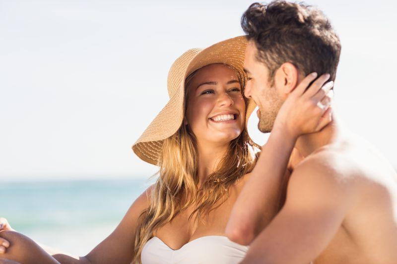 在海滩上坐在男友怀里的女友