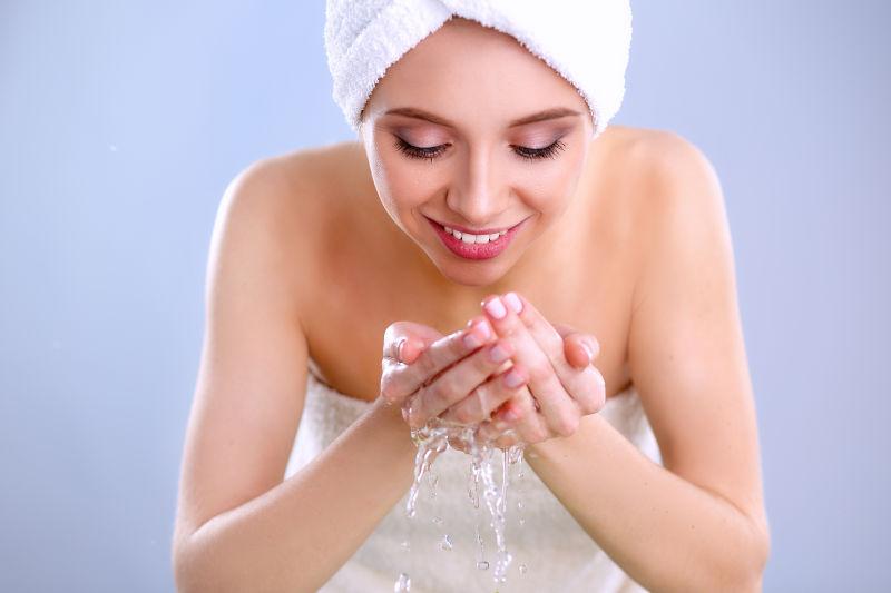 穿浴袍用清水洗脸的美女