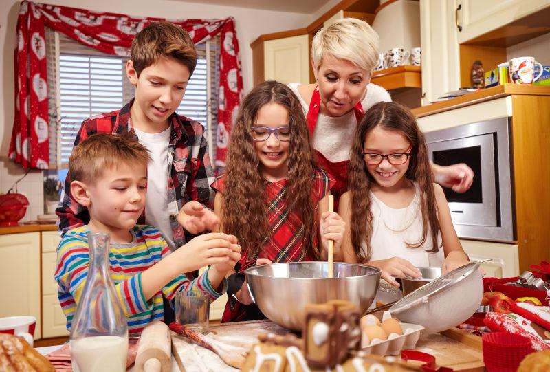 在厨房和妈妈一起准备圣诞节糕点的孩子们