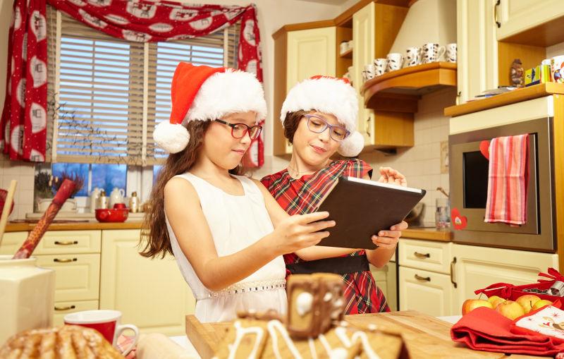 带着圣诞帽的孩子们浏览平板电脑