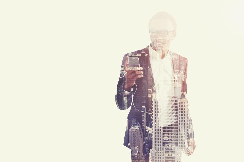 城市背景和听智能手机上音乐的商人的双重曝光