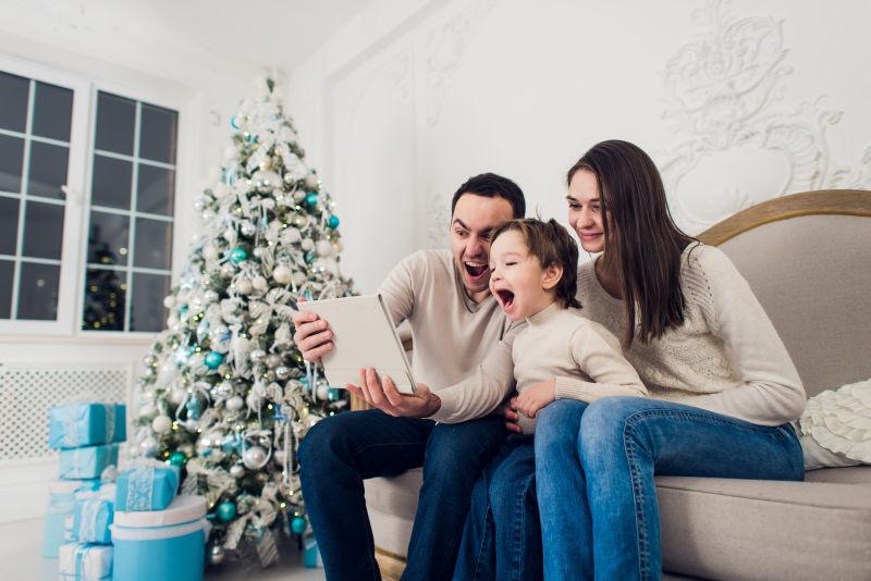 在圣诞树室内看平板电脑的一家人
