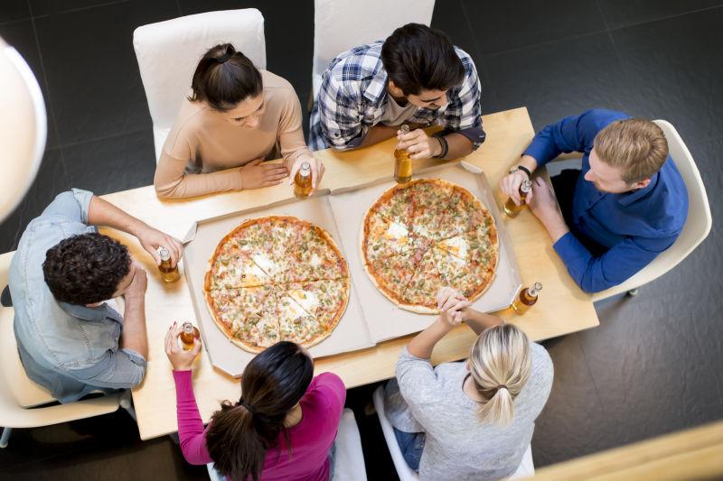 吃着披萨干杯的年轻帅气的朋友们