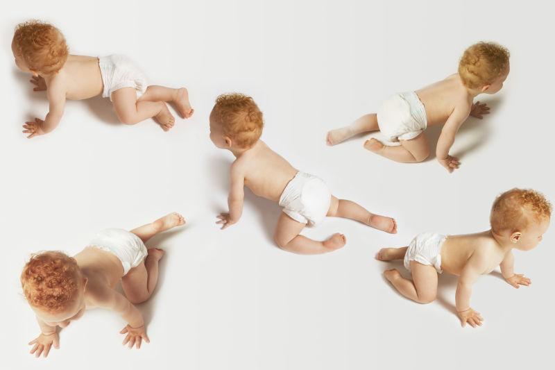 白色背景中不同方向爬行的男婴