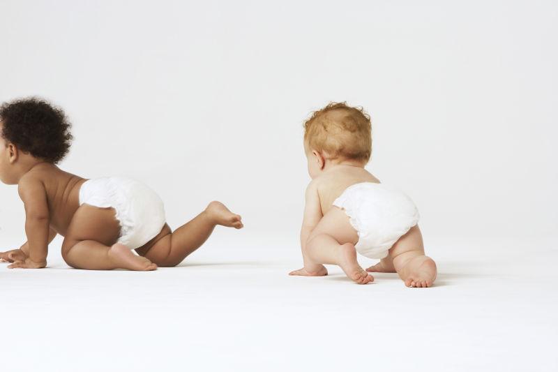 在白色背景下爬行的不同种族的男婴