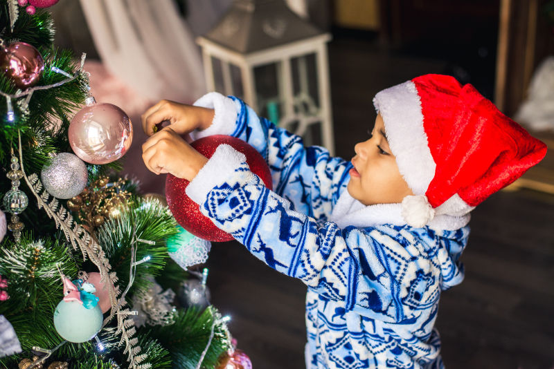 男孩为圣诞树挂彩球