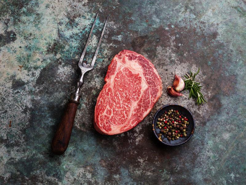 老旧木桌上的爱尔兰生牛排调味料和工具叉