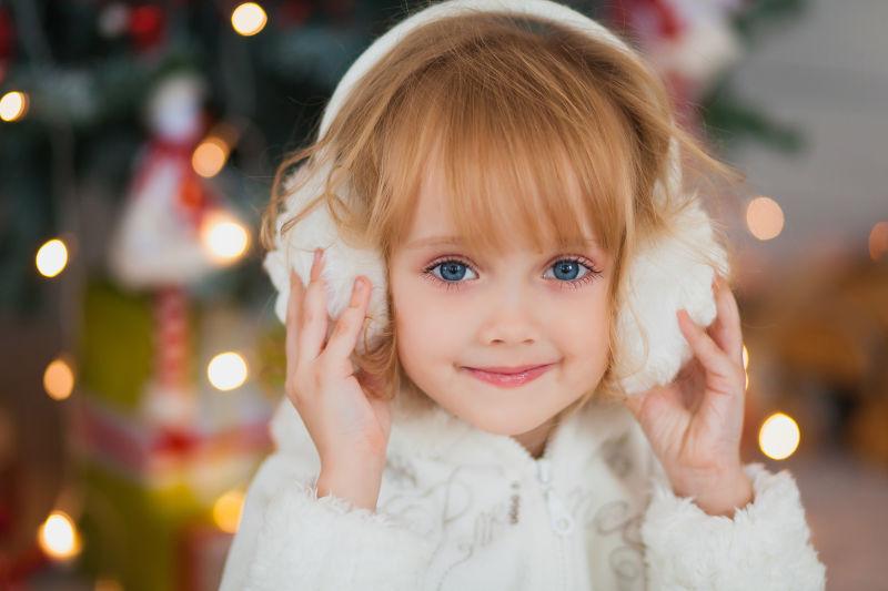 戴着温暖的白色耳机的漂亮女孩