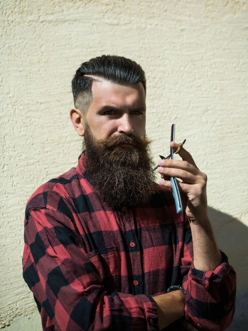 男人靠墙拿着剃刀