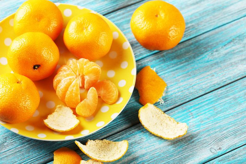 蓝色木桌上黄盘里的成熟的柑橘