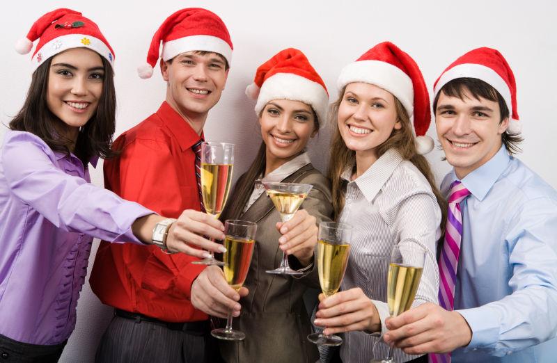 带着圣诞帽的五个人举着香槟庆祝
