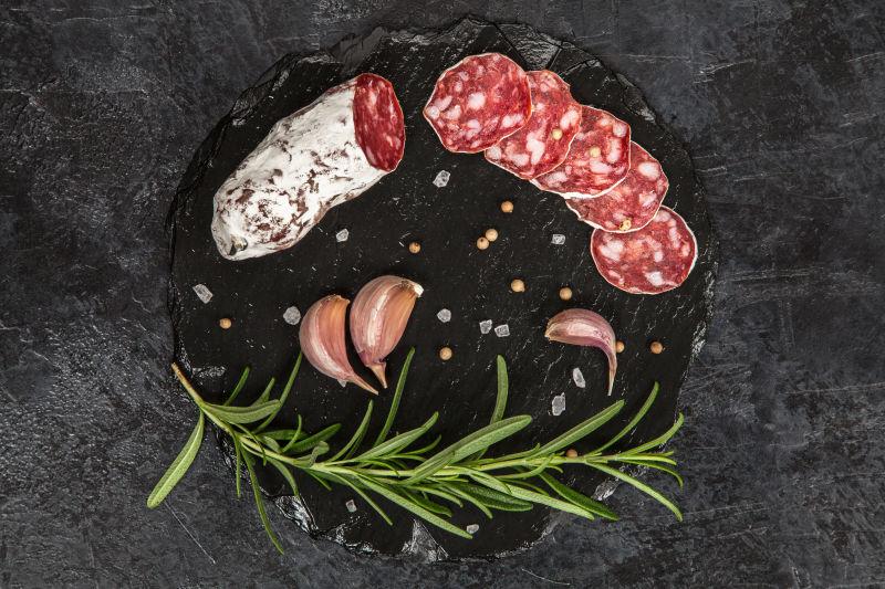 黑色砧板上的腊肠和迷迭香