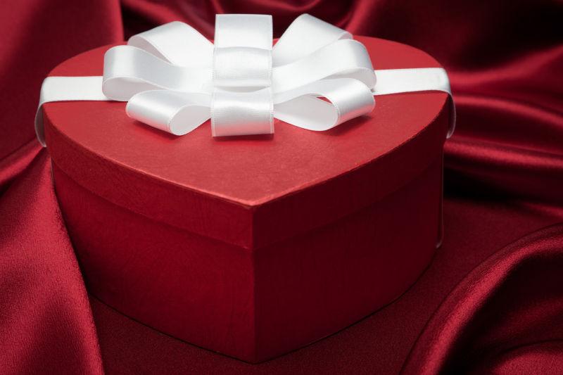 红缎背景下的红色心形礼品盒