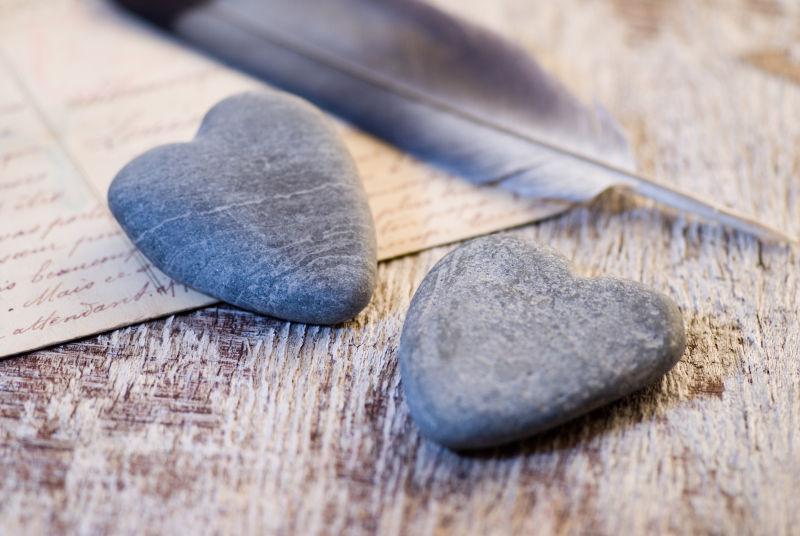 旧木桌上的明信片和心形石头