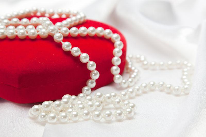 白色缎纹背景下的红色心形首饰盒