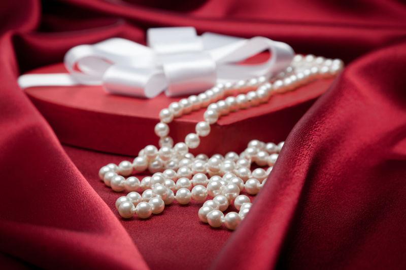 红色缎纹背景下的红色心形首饰盒