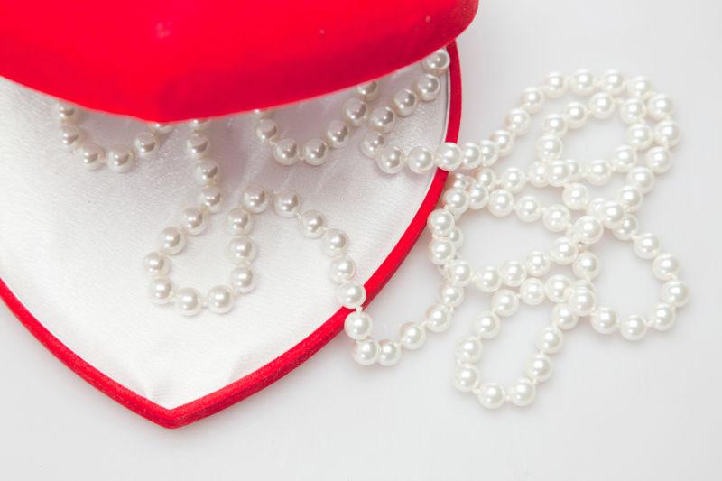 白色背景下红色心形首饰盒里的珍珠饰品