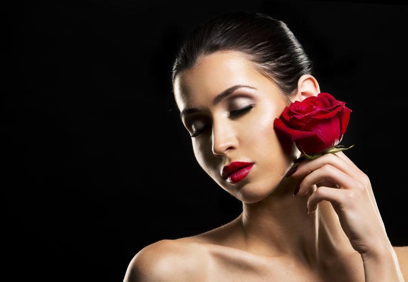 闭着眼睛的美女拿着红玫瑰