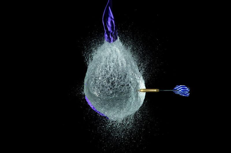 被飞镖射中的装满水的蓝色气球