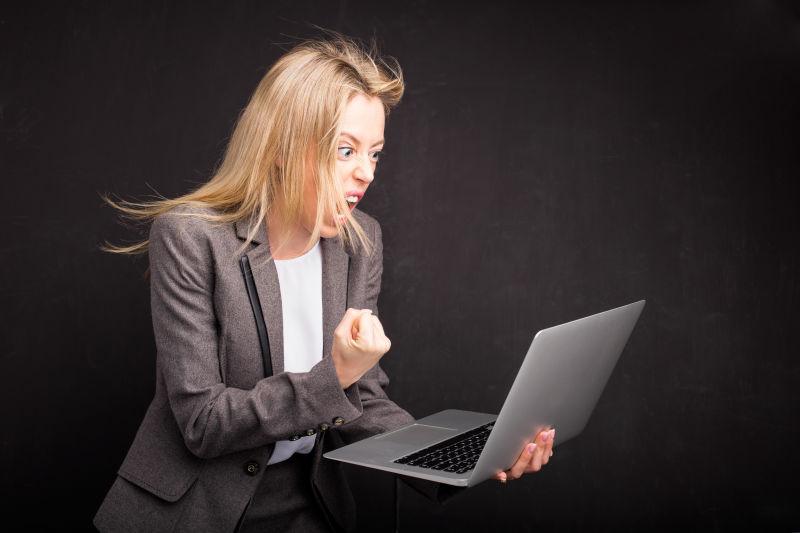 黑色背景中女人生气的拿电脑