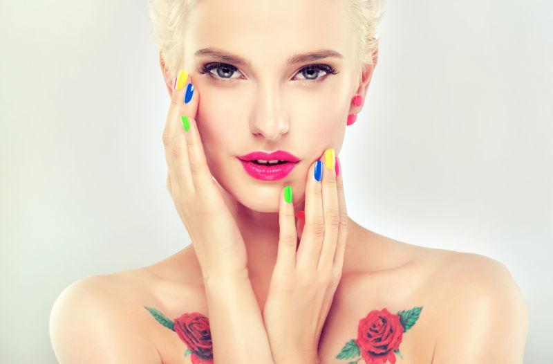 双手有彩色美甲和玫瑰纹身的化妆美女