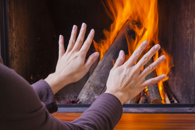 女子在壁炉旁暖手