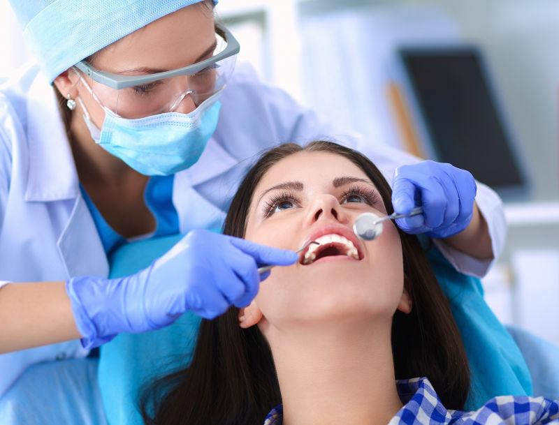 正在为美女病人检查牙齿的牙医