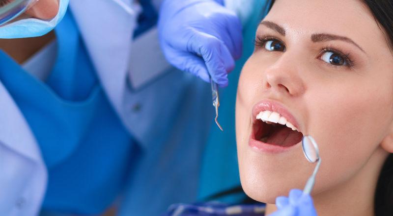 张开嘴巴检查牙齿的牙医和病人