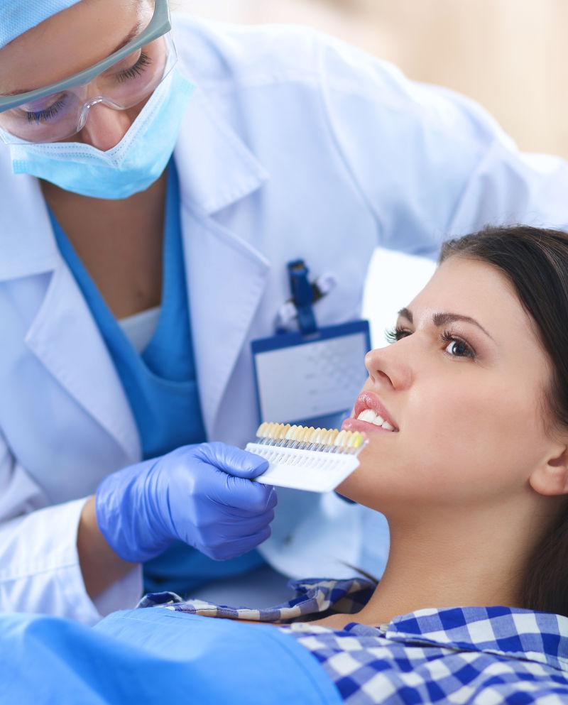 正在为病人检查牙齿颜色的牙医