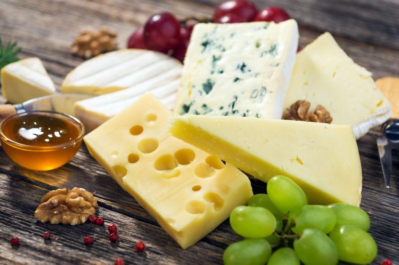木桌上的各种奶酪和葡萄等美食