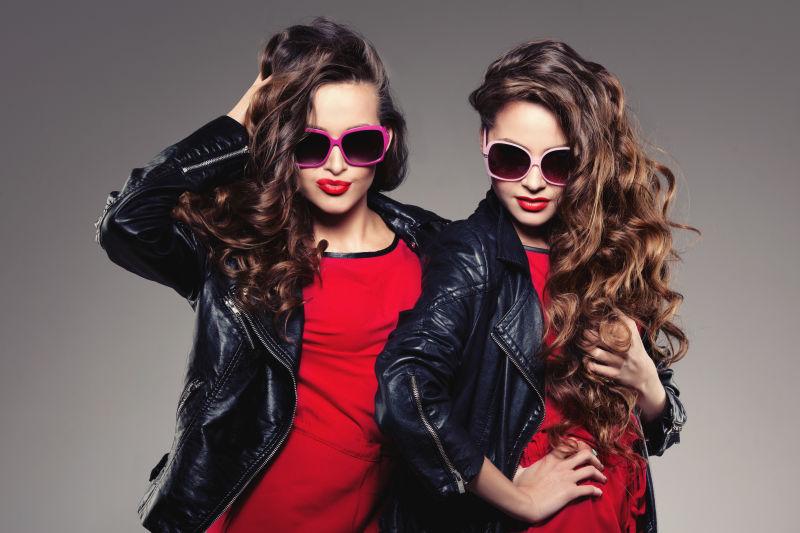 灰色背景下穿着黑色皮衣的棕色卷发美女