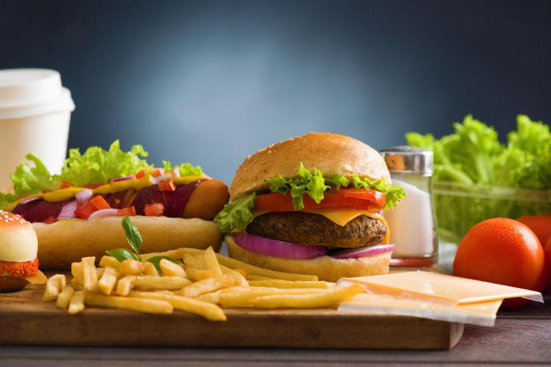 桌子上的蔬菜和美味汉堡薯条热狗