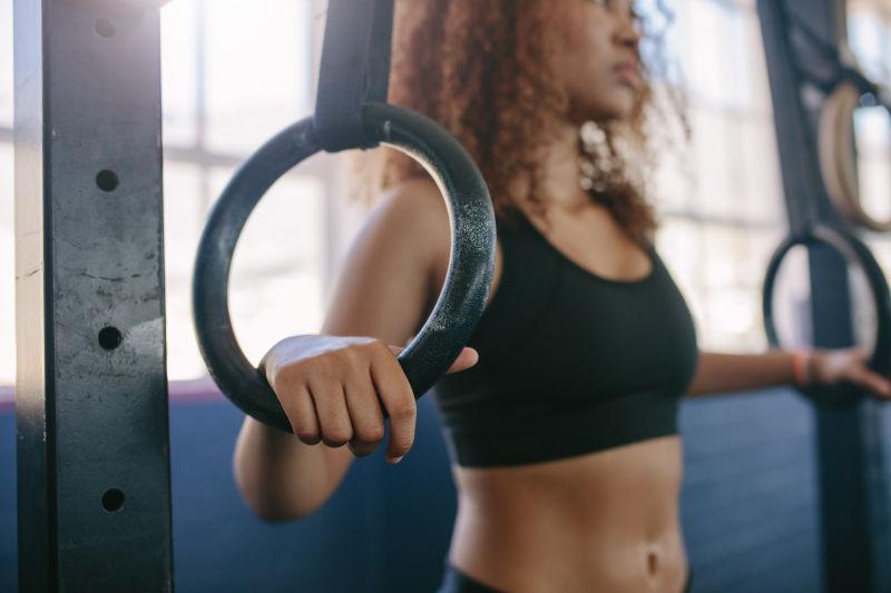 健身房背景中在体操环上运动的美女