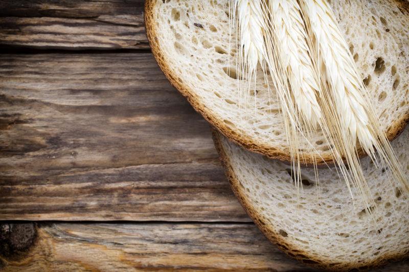 木桌上的切片面包和麦穗