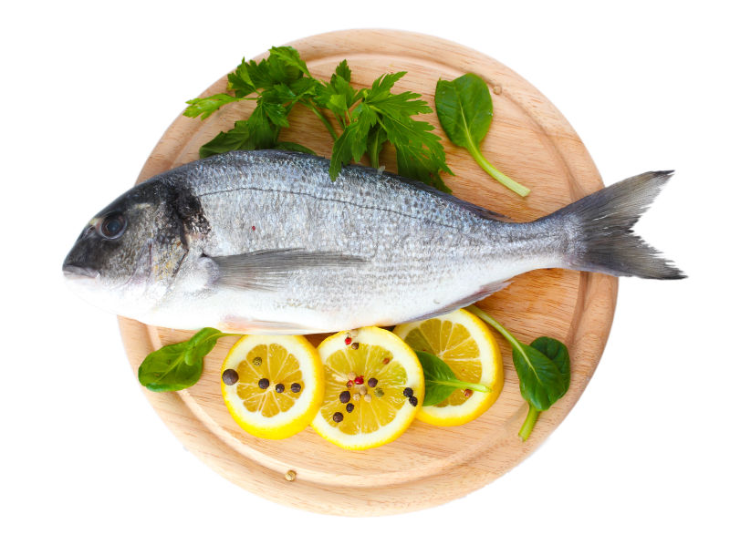 一条新鲜的鱼与柠檬片还有一些蔬菜