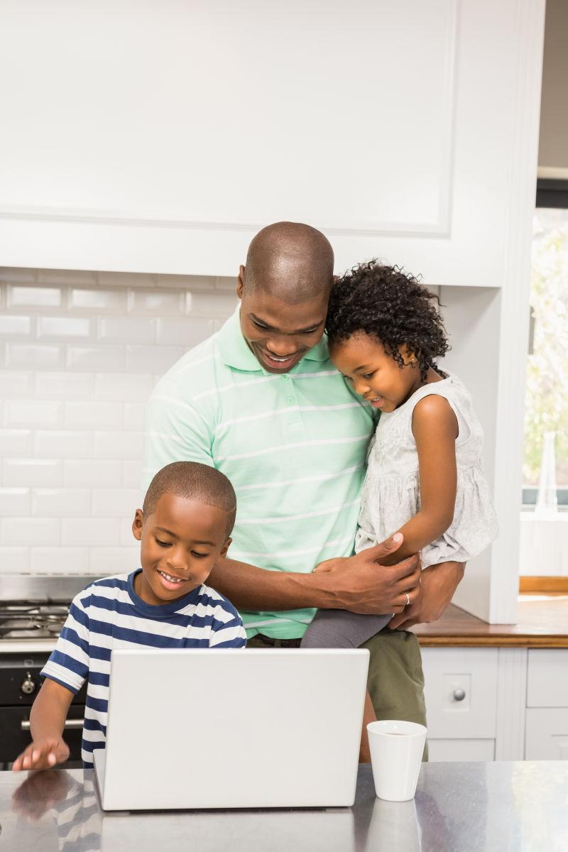 在厨房里使用笔记本电脑的快乐家庭