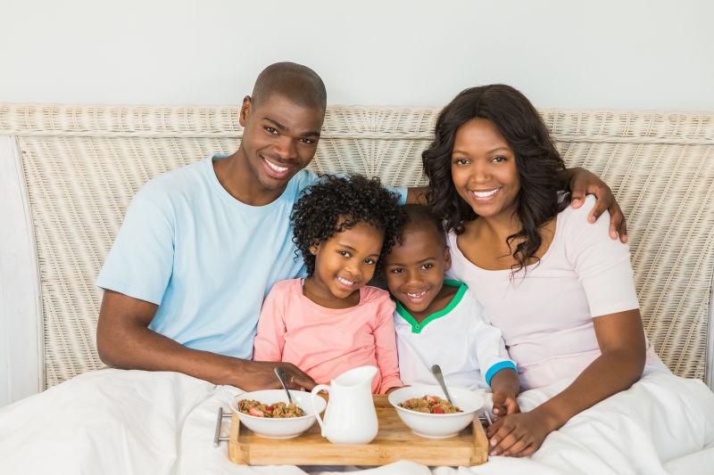 快乐的家人早上一起在床上吃早餐