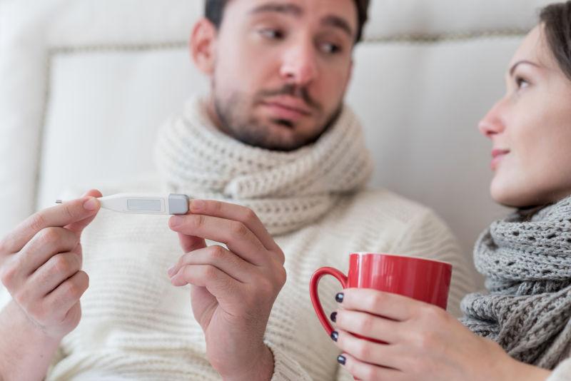 床上一对看着温度计的情侣