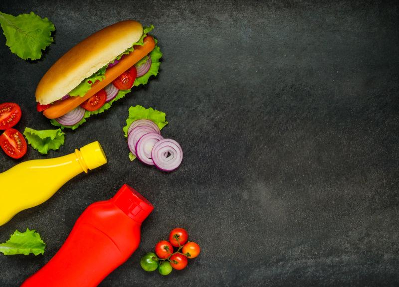 黑色桌子上的美味热狗和酱料