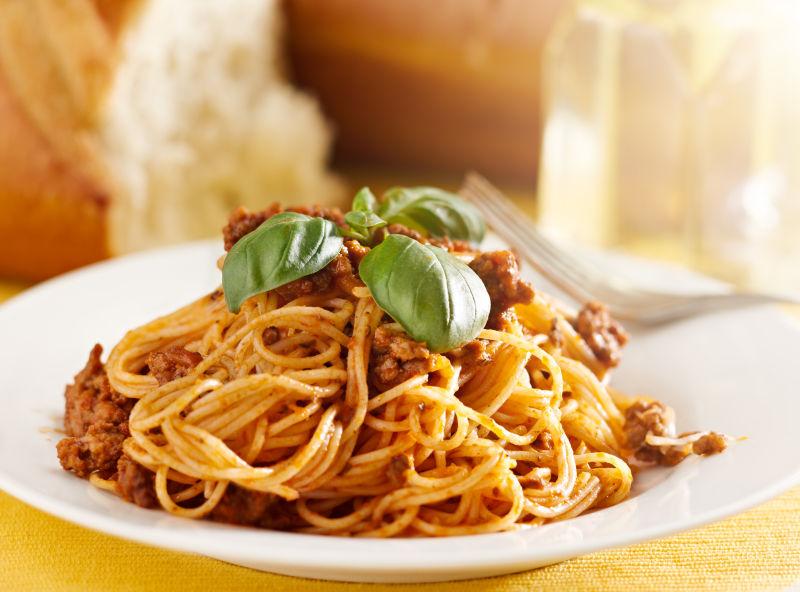 桌子上放着薄荷叶和肉酱的意大利面
