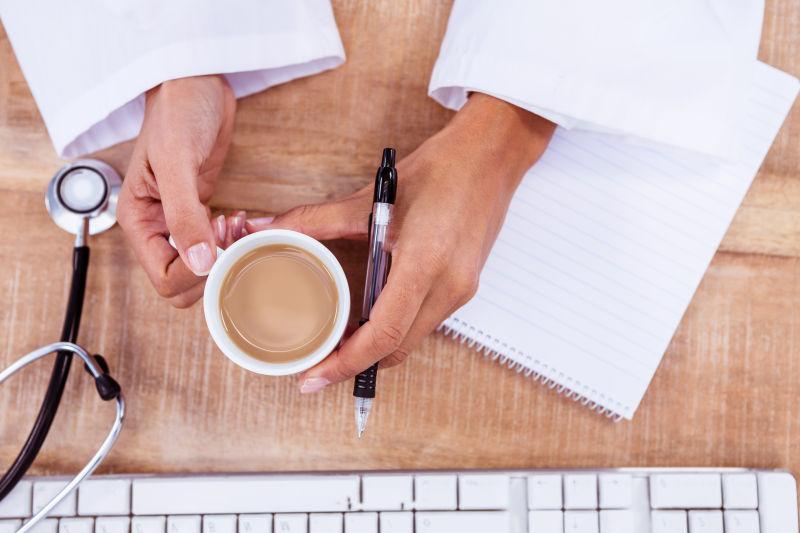 办公桌前喝咖啡提神儿的医生