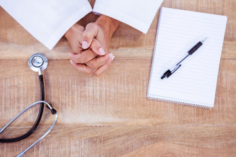 在有听诊器的办公桌上做笔记的医生