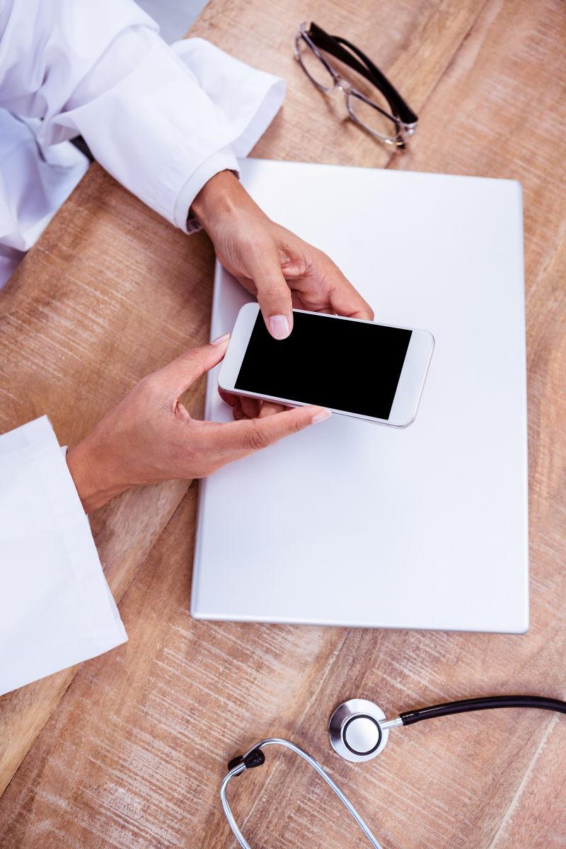 笔记本背景前使用智能手机的医生