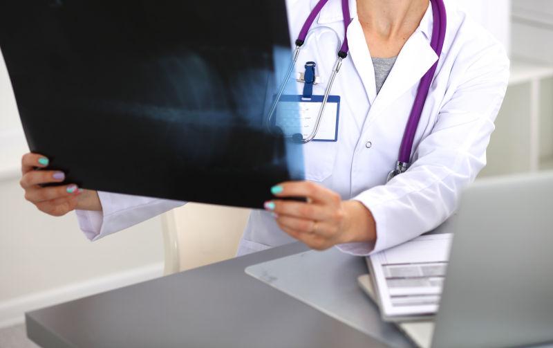 穿着白色外套的年轻女医生在电脑旁边