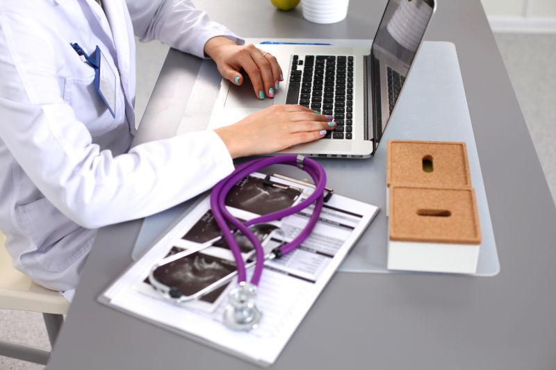 穿着白色外套的年轻医生在电脑上工作