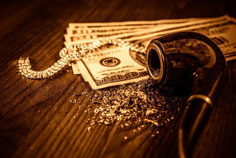 木桌上的美元纸币和装烟丝的烟斗